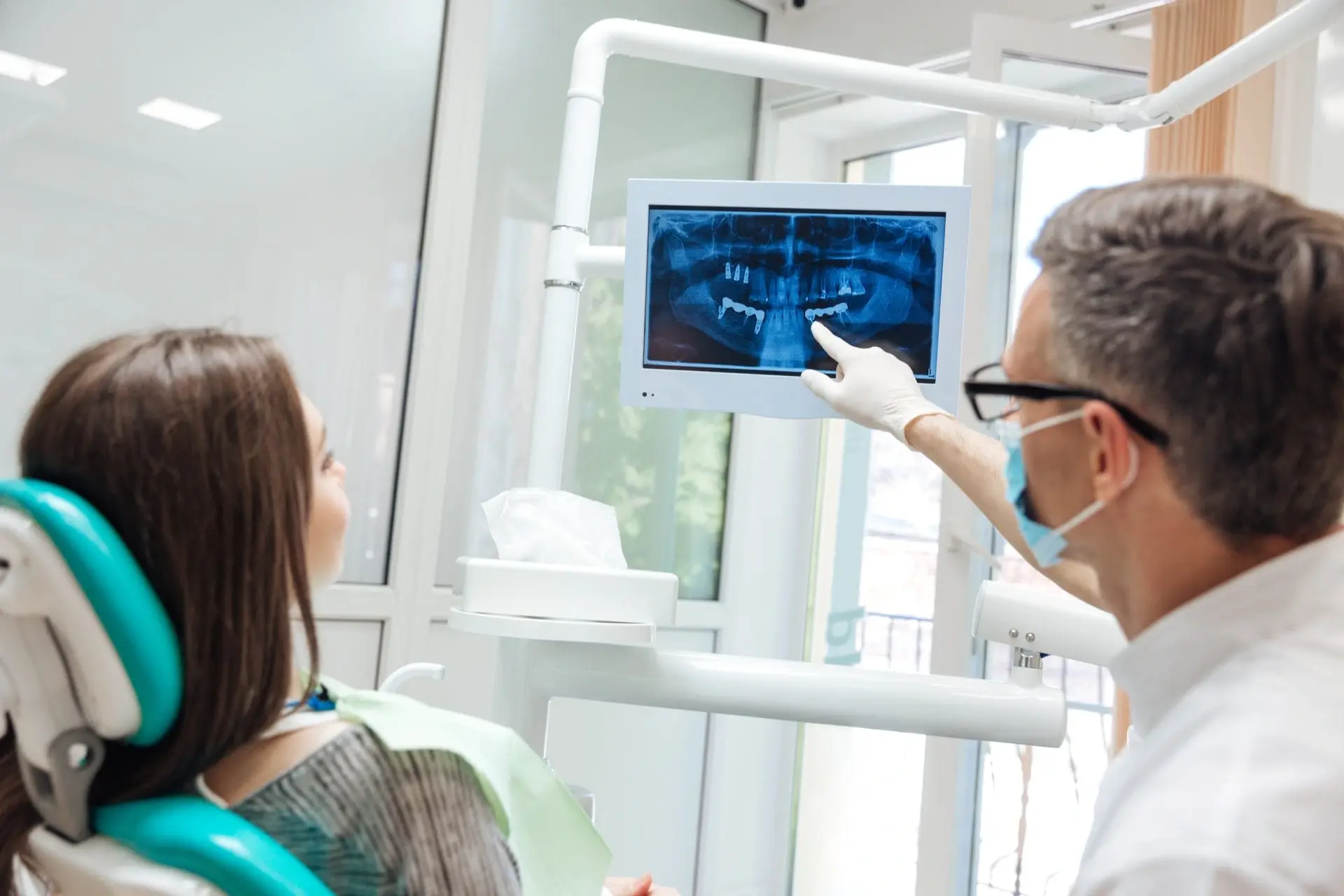 Dentist reviewing dental X-ray with patient in Albuquerque treatment room.
