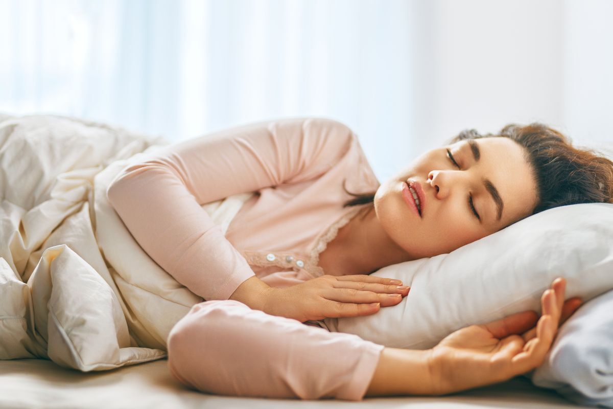 Woman sleeping peacefully on white pillow and bedding, illustrating restful sleep related to sleep apnea treatment.