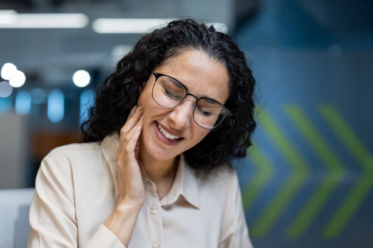 Woman with glasses smiling, relieved from dental pain at Albuquerque dental office.