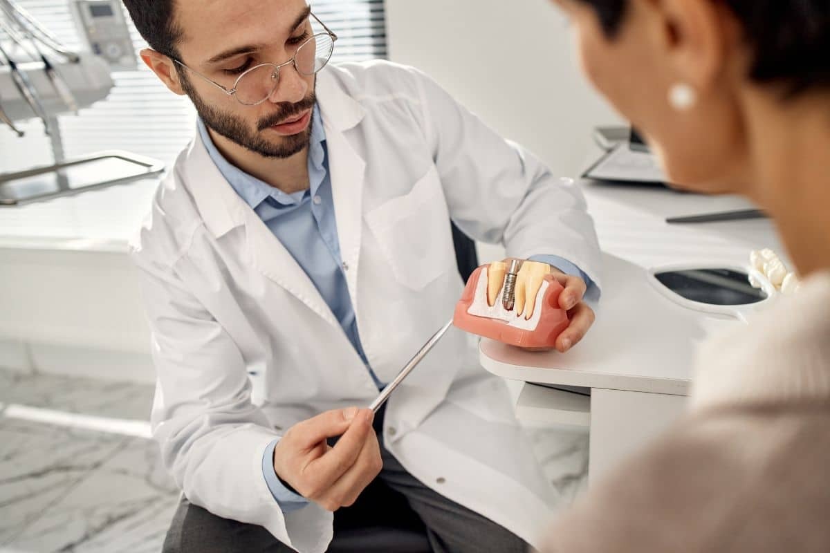 Dentist explaining dental implant model to patient during consultation in Albuquerque office.