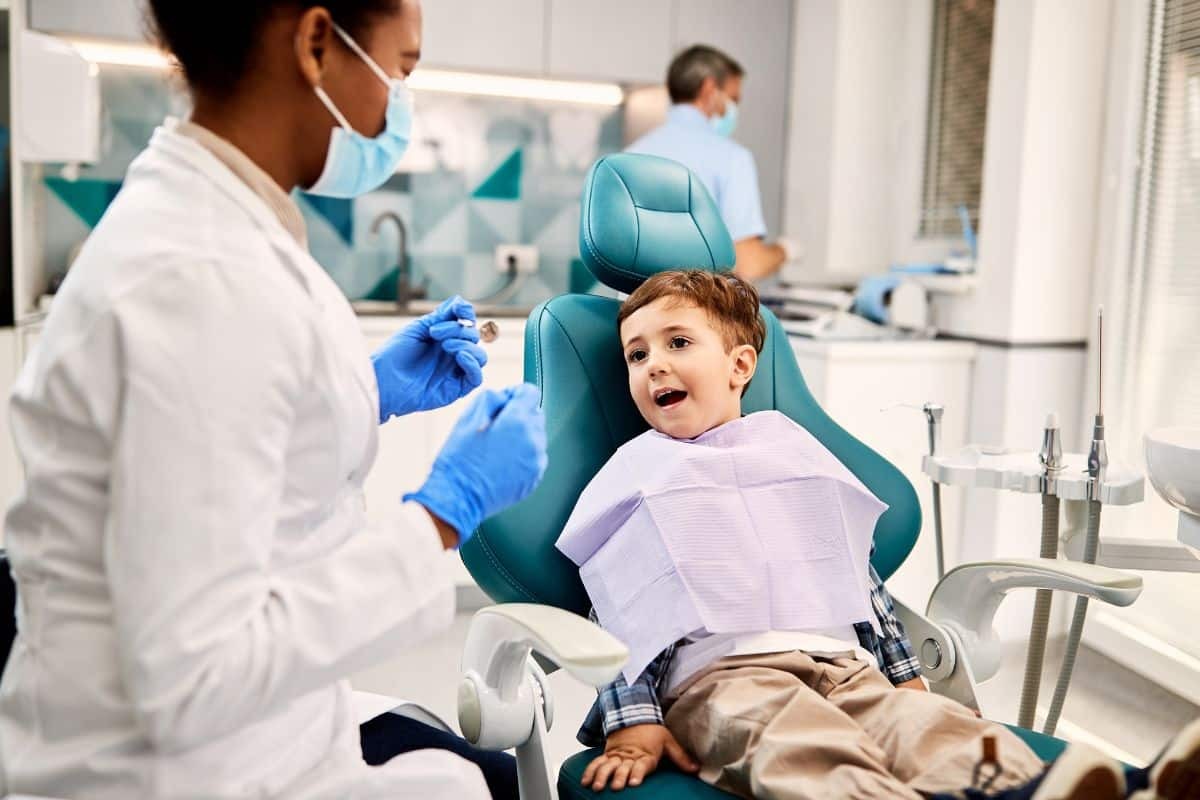 Young boy in dental chair smiling during checkup with pediatric dentist in Albuquerque.