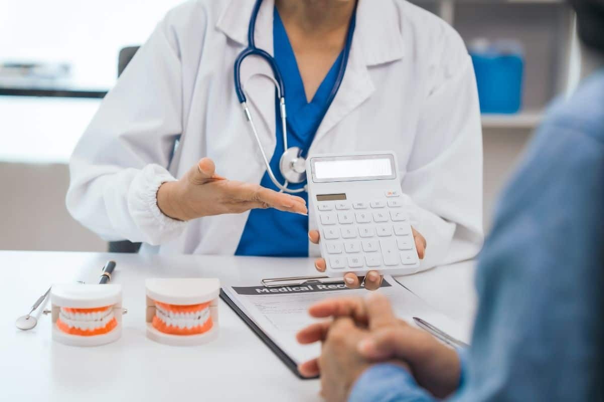 Dentist showing calculator to patient during consultation at dental practice in Albuquerque.