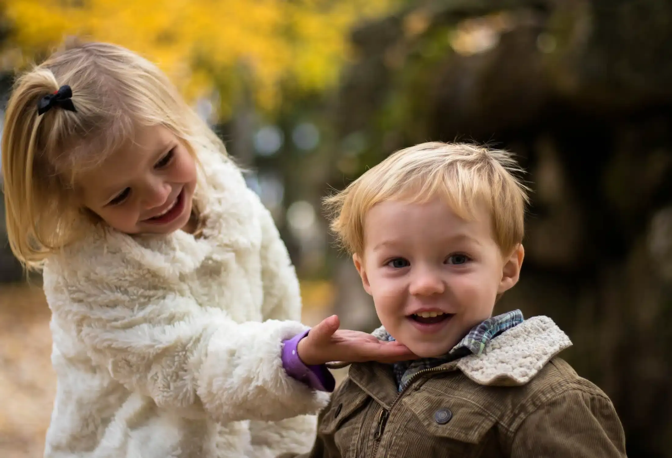 Two young children smiling outdoors, promoting pediatric dental care in Albuquerque.